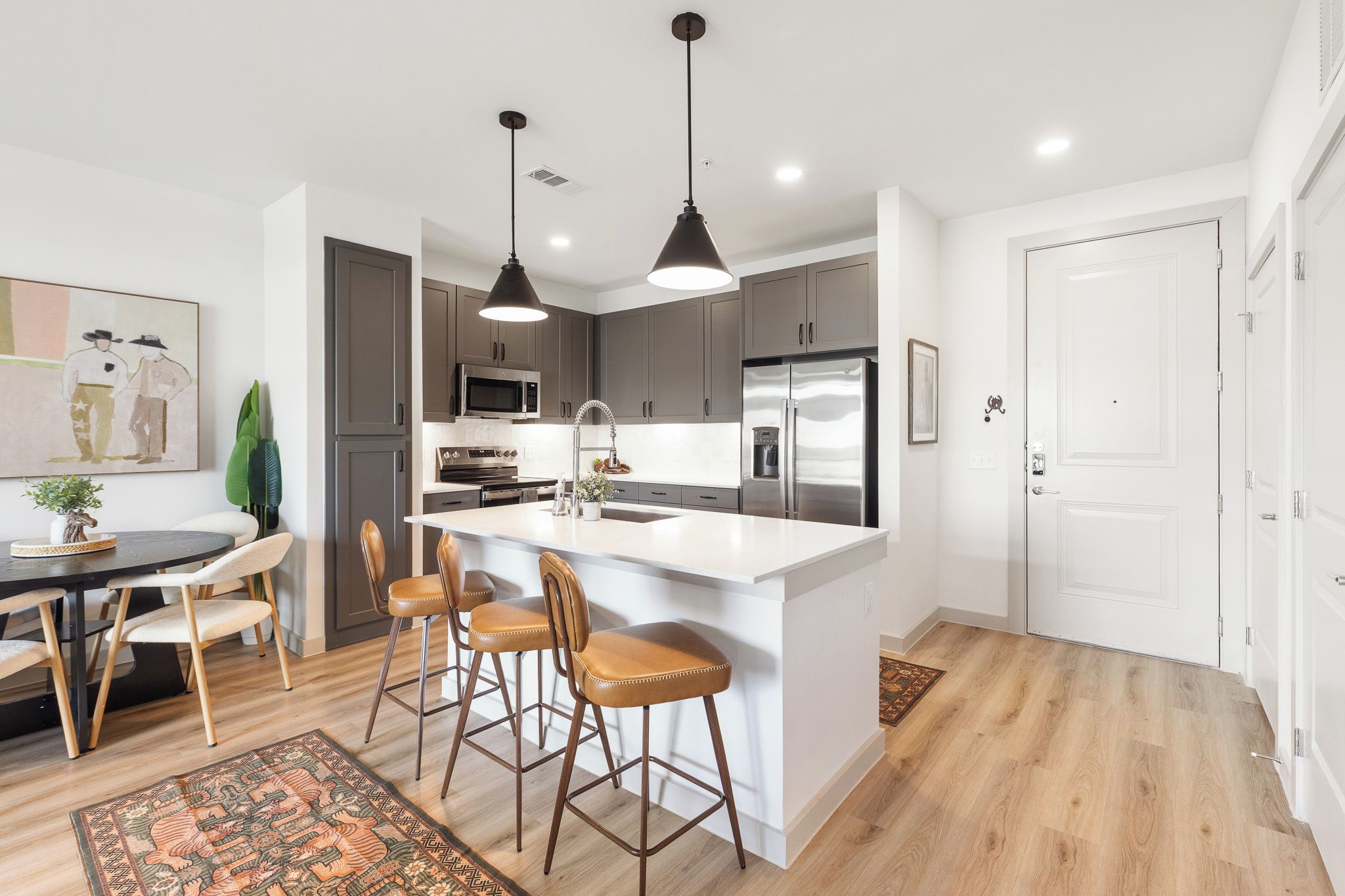 A modern kitchen with a central island, bar stools, and pendant lighting.