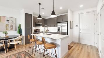 A modern kitchen with a central island, bar stools, and pendant lighting.