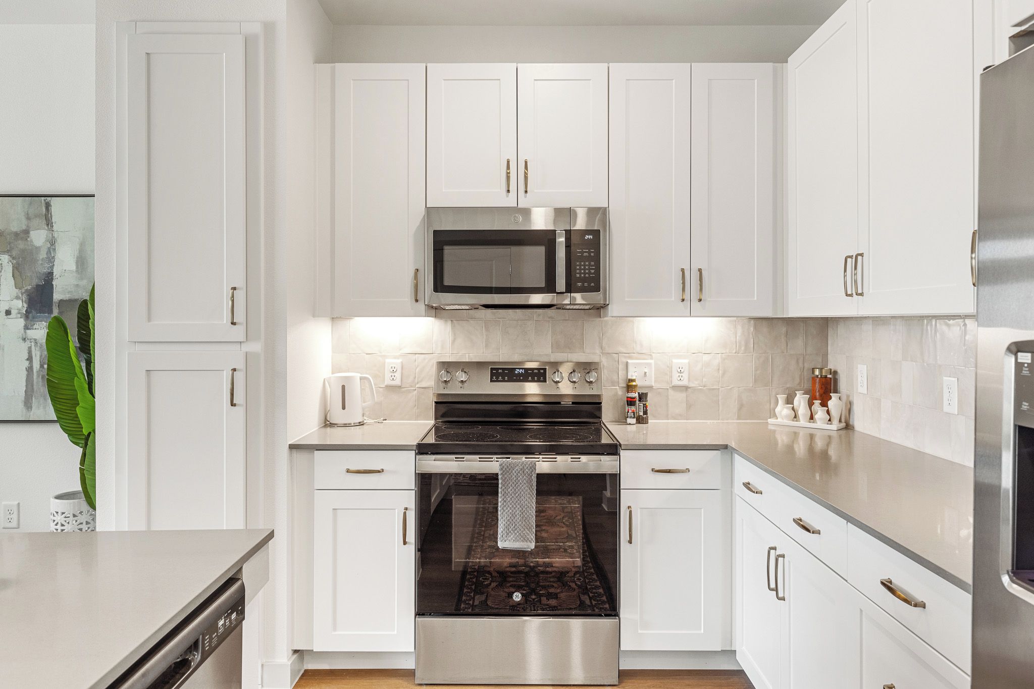 A modern kitchen with white cabinets, stainless steel appliances, and a central island.
