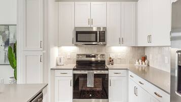 A modern kitchen with white cabinets, stainless steel appliances, and a central island.