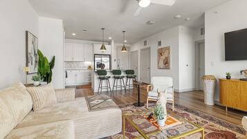 A modern living room with a sofa, a coffee table, and a dining area with chairs.