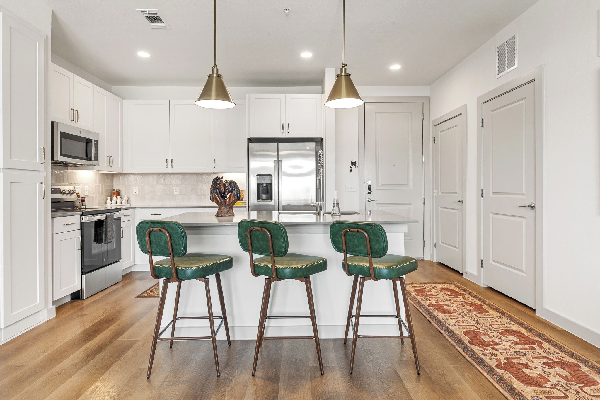 A modern kitchen with white cabinets, stainless steel appliances, and a central island with bar stools.