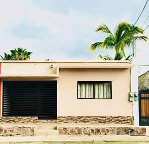 A single-story building with a flat roof, a large garage door, and a small window. - Casa Madero #1, 1 block from the Malecón (La Paz)