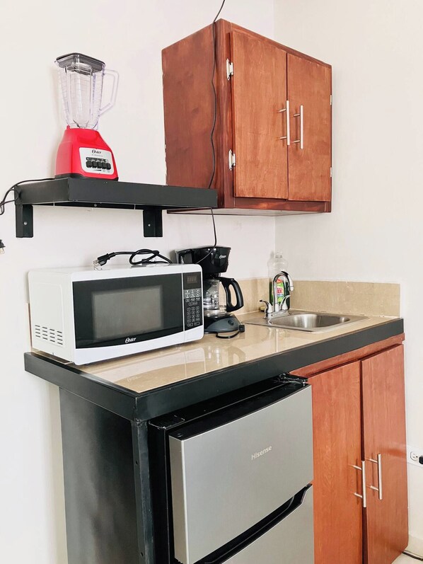 Eine kleine Küche mit Mikrowelle, Kaffeemaschine, Mixer und Holzschränken.