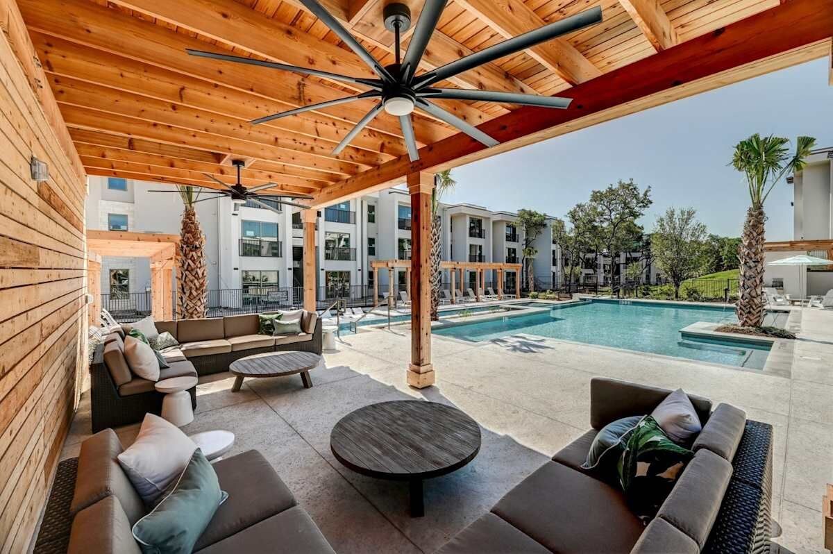 A covered outdoor area with a pool, wooden ceiling, and lounge furniture.