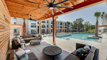 A covered outdoor area with a pool, wooden ceiling, and lounge furniture.
