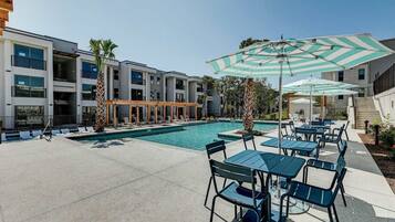 A modern hotel with a swimming pool, outdoor seating, and a covered patio area.