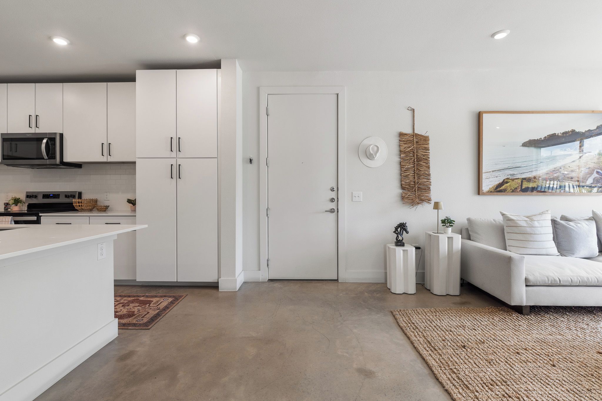 A modern kitchen with white cabinets, a microwave, and a dining area with a white table and chairs.