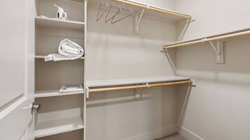A walk-in closet with open shelves, a hanging rod, and a door with a silver handle.