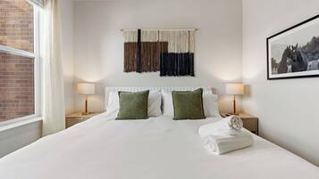 A hotel room with a large bed, two bedside tables with lamps, a wall-mounted tapestry, and a framed picture.