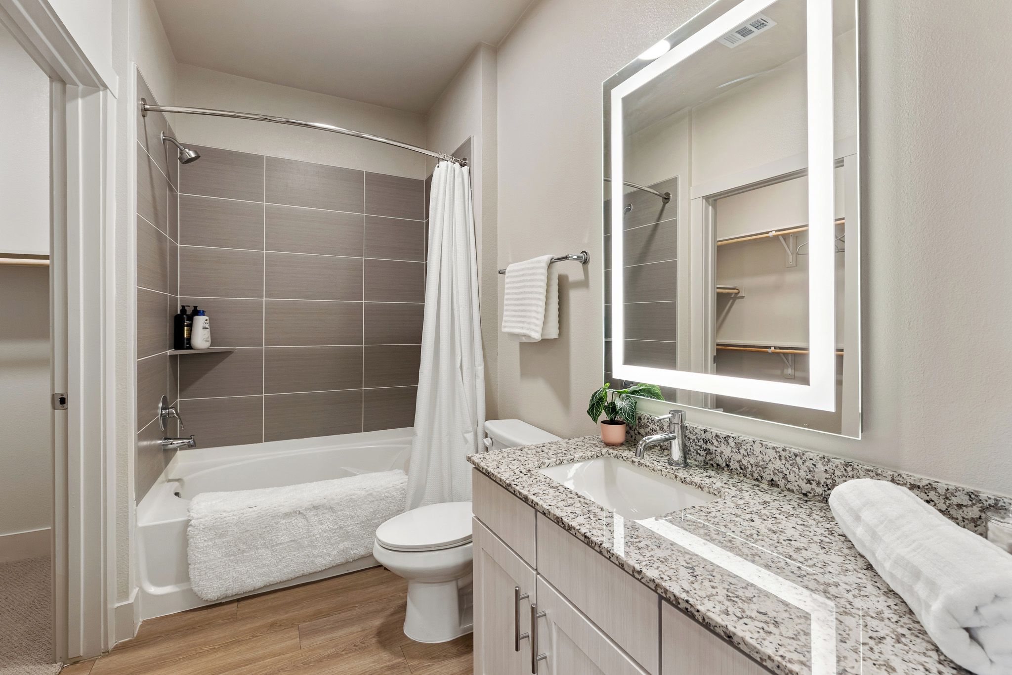 A modern bathroom with a bathtub, toilet, sink, and a large mirror.