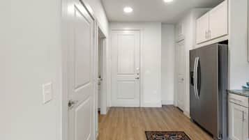 A kitchen with white cabinets, a stainless steel refrigerator, and a wooden floor.