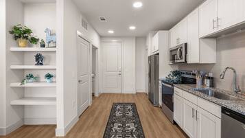 A modern kitchen with white cabinetry, a stainless steel refrigerator, a microwave, and a dishwasher.