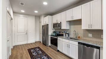 A modern kitchen with white cabinets, stainless steel appliances, and a granite countertop.