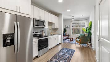 A modern kitchen with stainless steel appliances, white cabinetry, and a patterned rug.