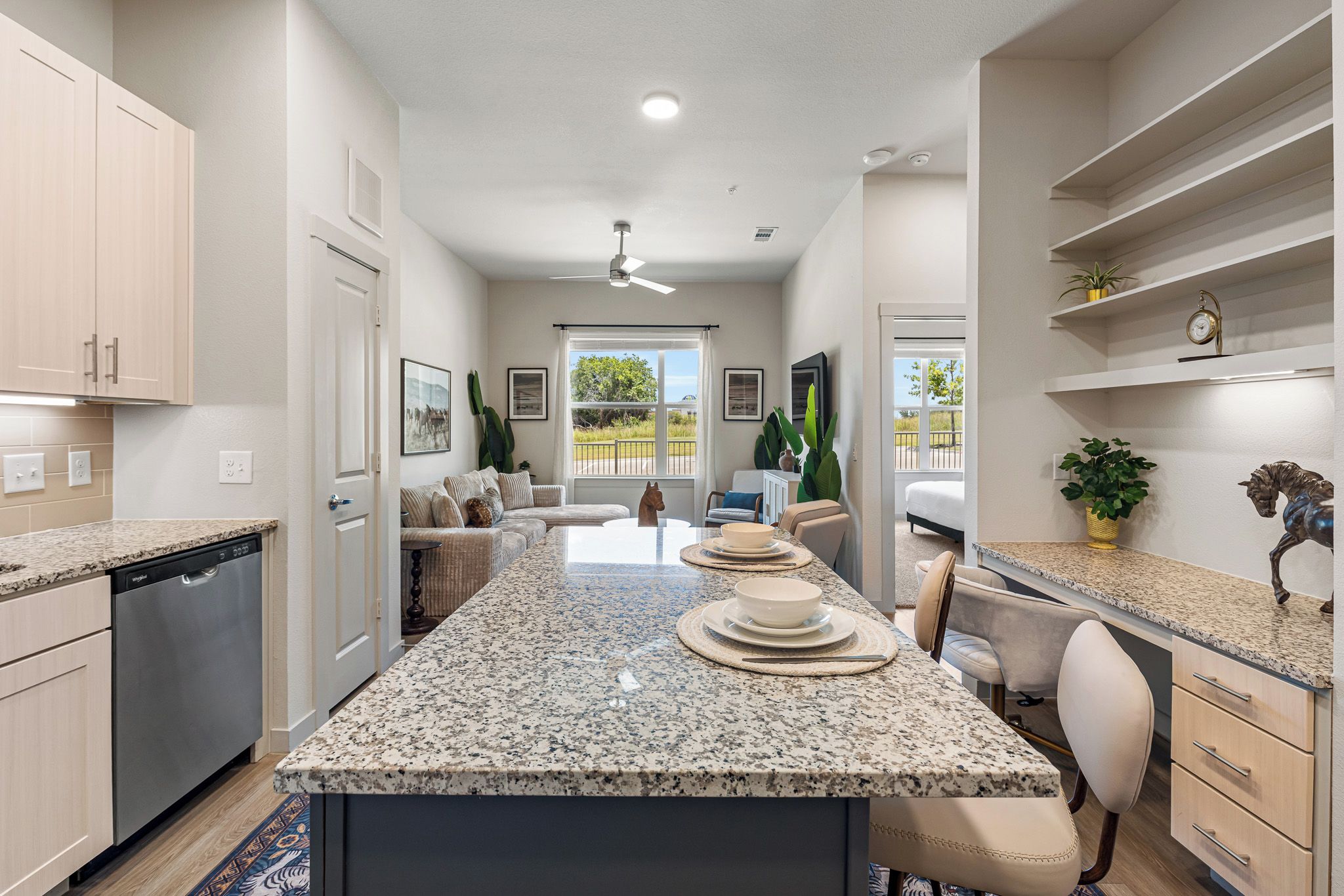 A modern kitchen with granite countertops, a dishwasher, and a dining area with a table set for four.