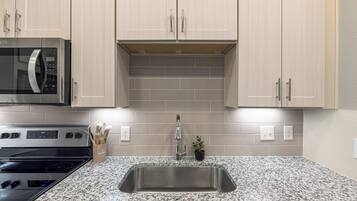 A kitchen with a stainless steel sink, granite countertop, and modern cabinetry.