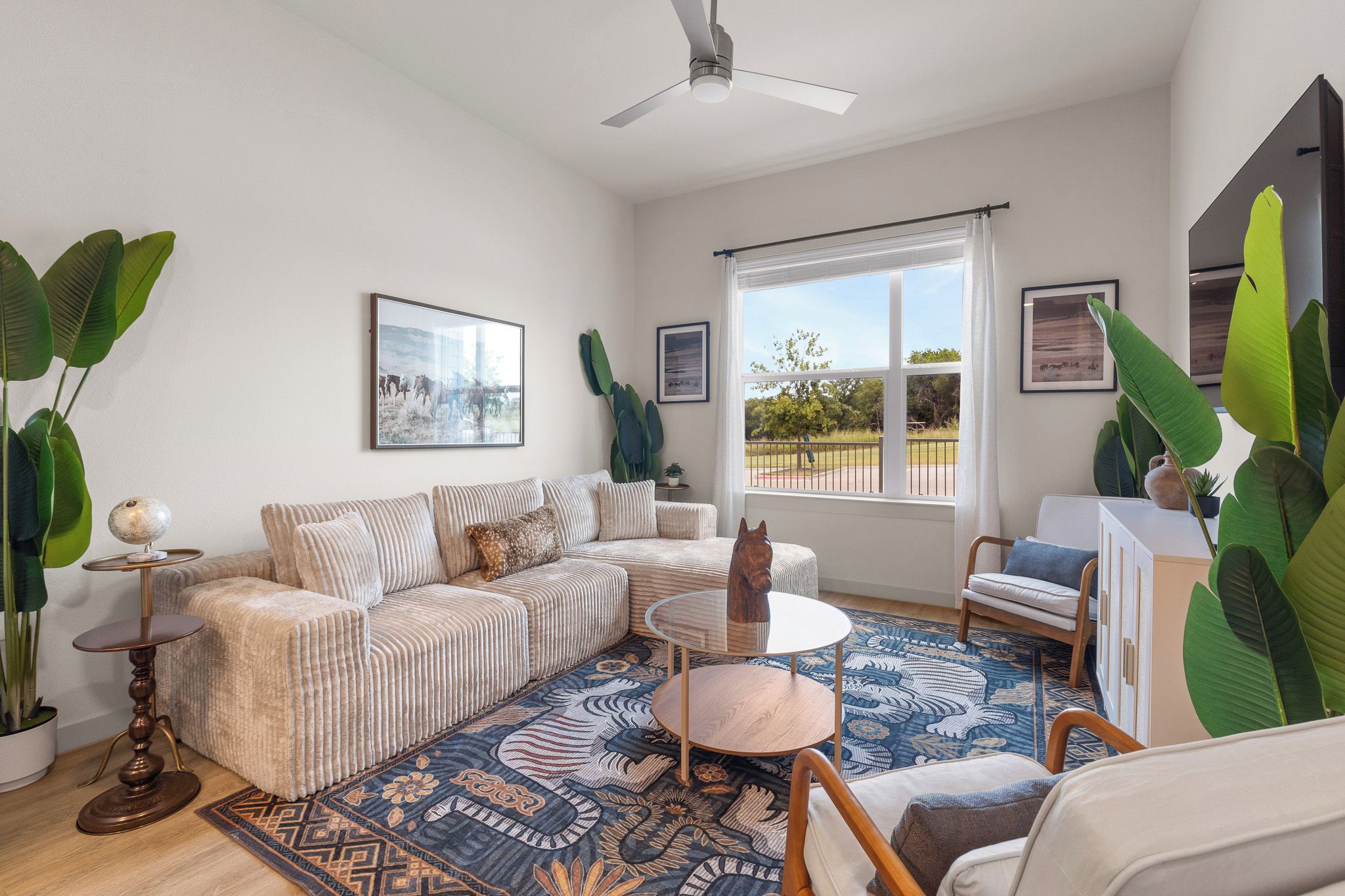 A spacious living room with a large sofa, a coffee table, and a view of the outdoors through a window.