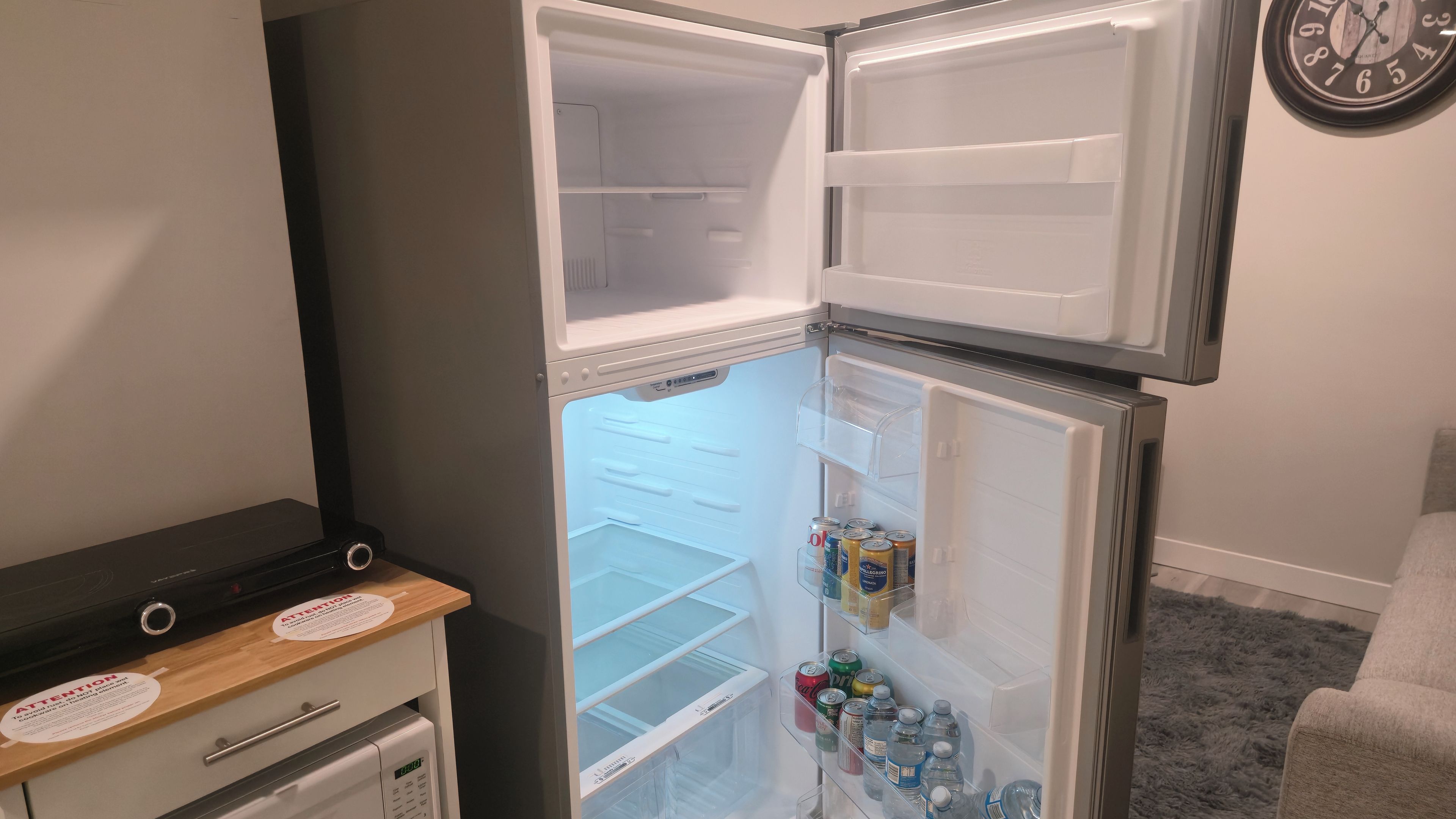 A compact refrigerator with a freezer compartment, a small freezer, and a shelf with beverages.