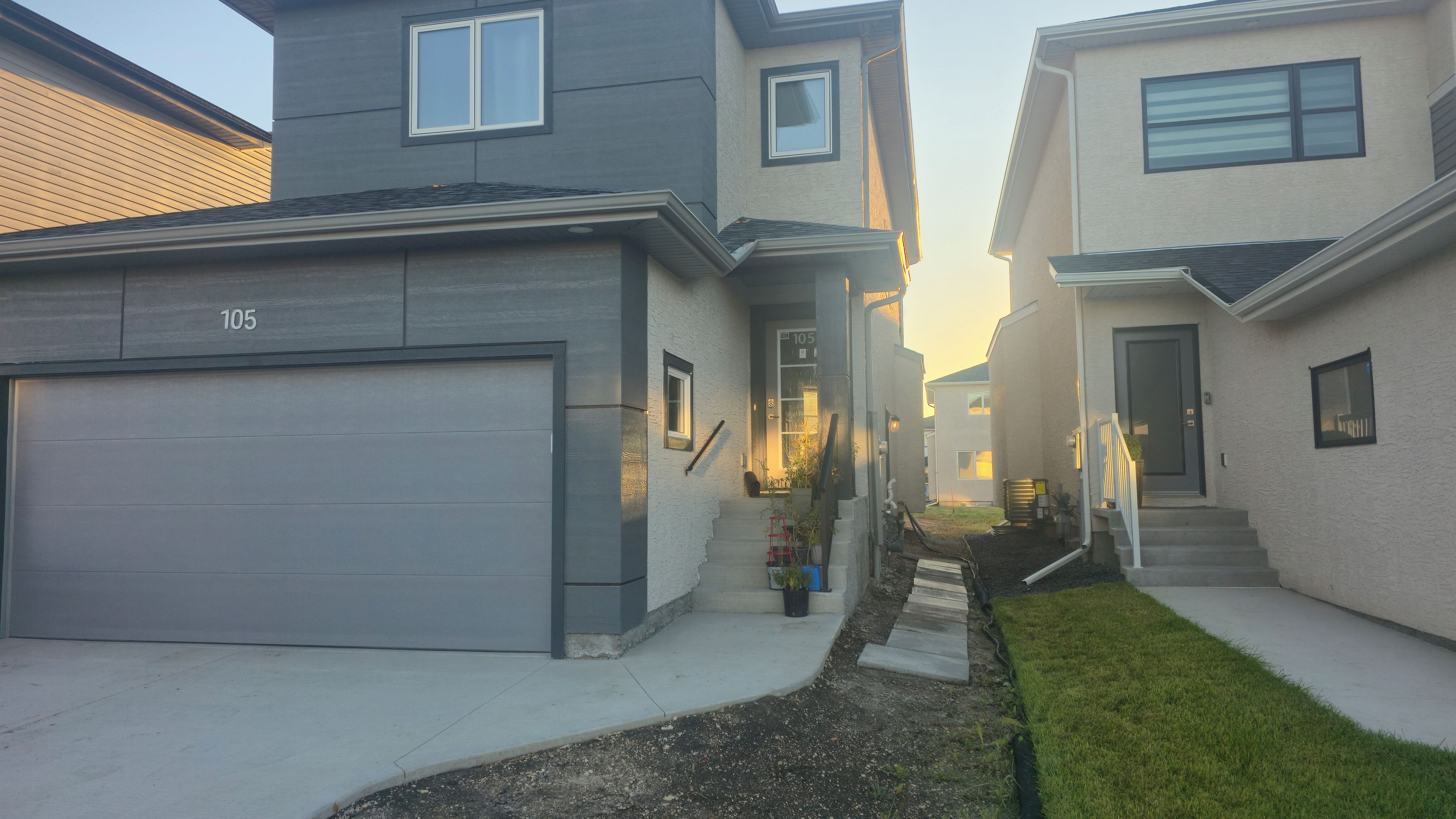 A residential street with houses, a garage, and a small garden area.