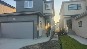 En bostadsgata med hus, ett garage och en liten trädgårdsyta.