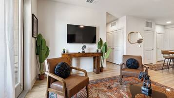 A living room with a TV, two leather chairs, a wooden coffee table, and a patterned rug.