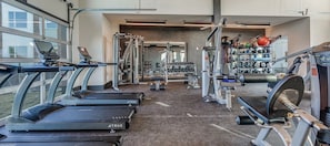 Ein Fitnessstudio mit Laufbändern, Kraftgeräten und Kurzhanteln.
