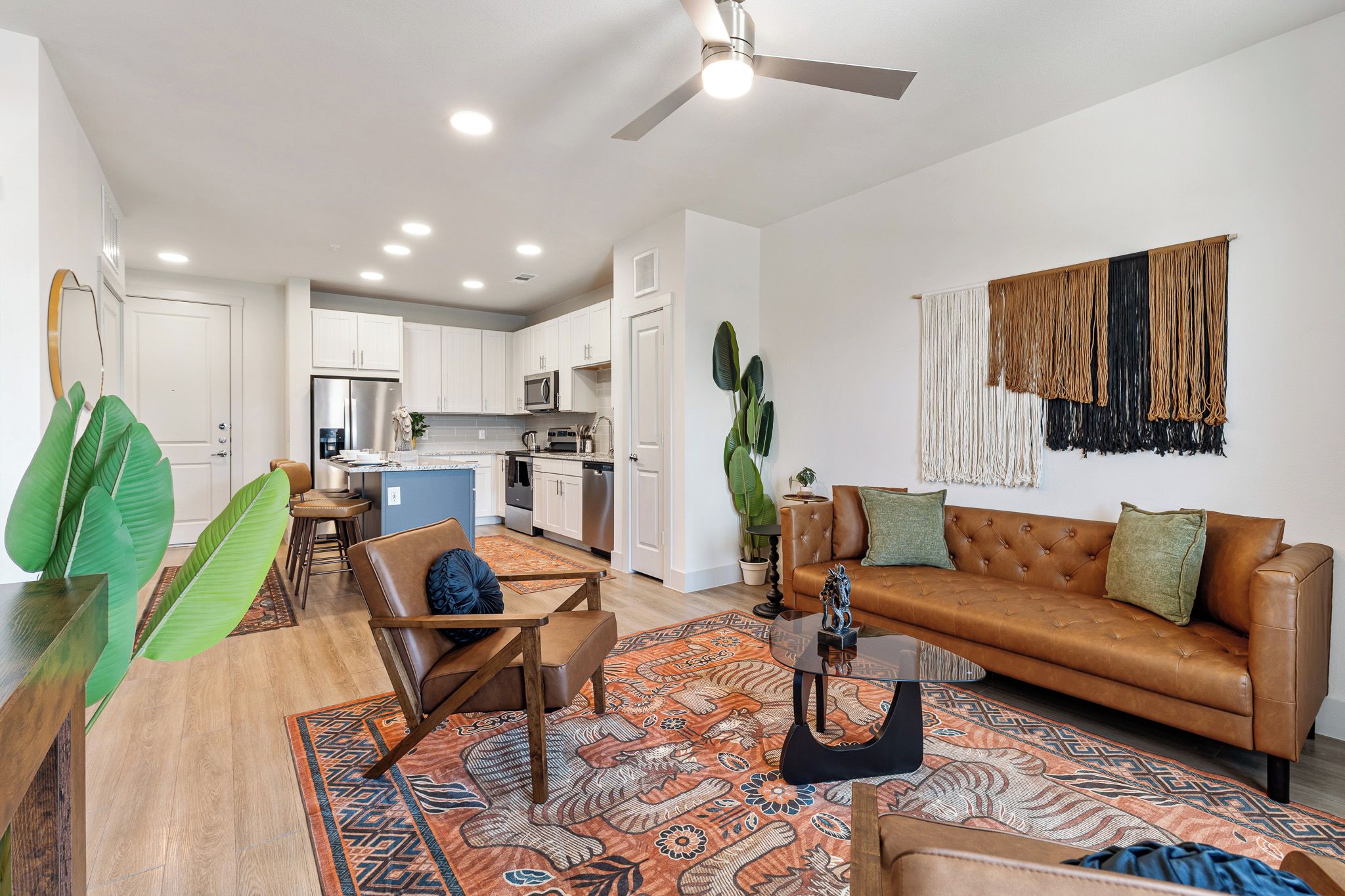 A modern living room with a brown leather sofa, a coffee table, and a patterned rug.