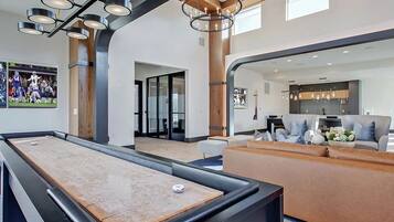 A billiards table in a modern room with a sofa and a mirror reflecting the room.