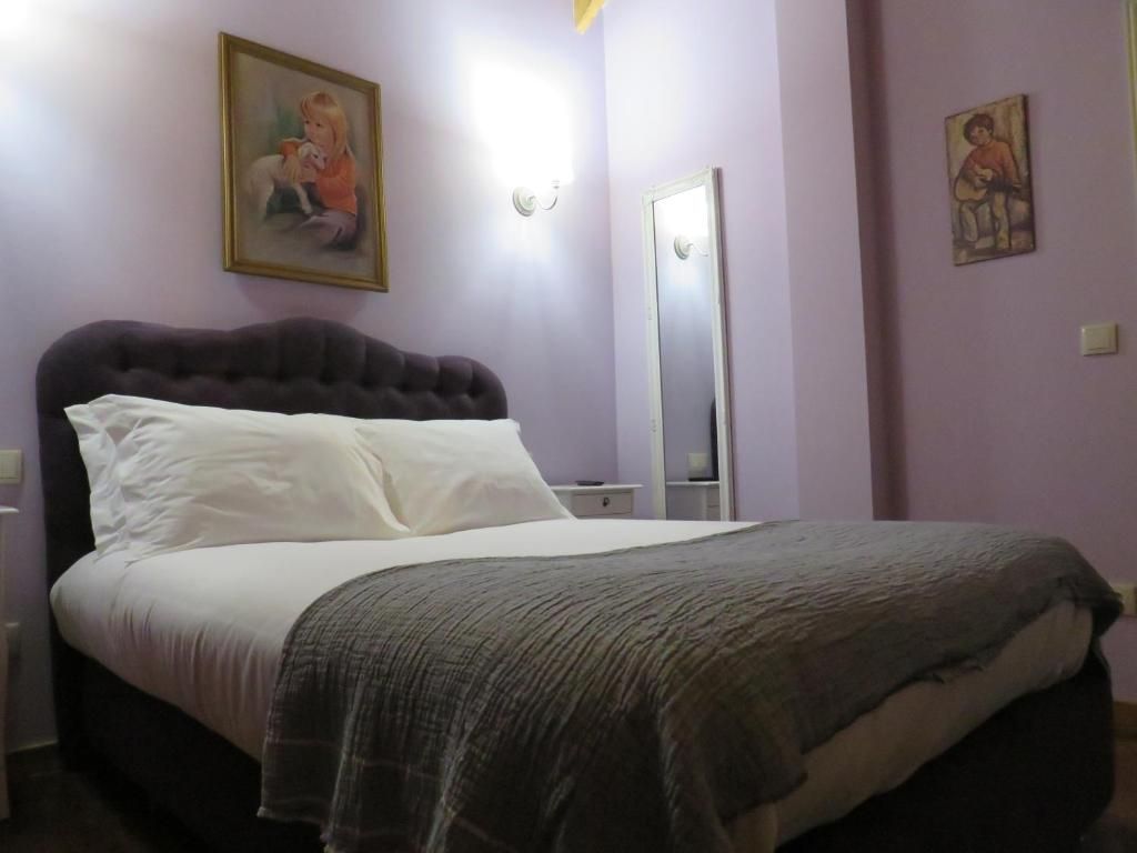 A bedroom with a large bed, a nightstand, a dresser, and a mirror.