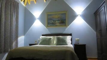 Un dormitorio con cama, mesitas de noche, un cuadro en la pared y un armario.