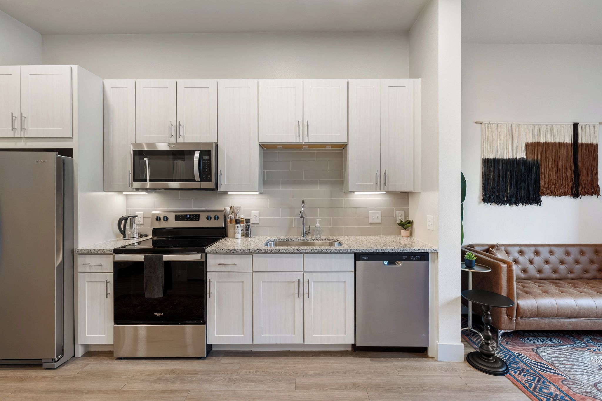 A modern kitchen with white cabinetry, stainless steel appliances, and a dishwasher.