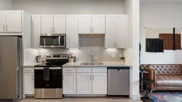 A modern kitchen with white cabinetry, stainless steel appliances, and a dishwasher.