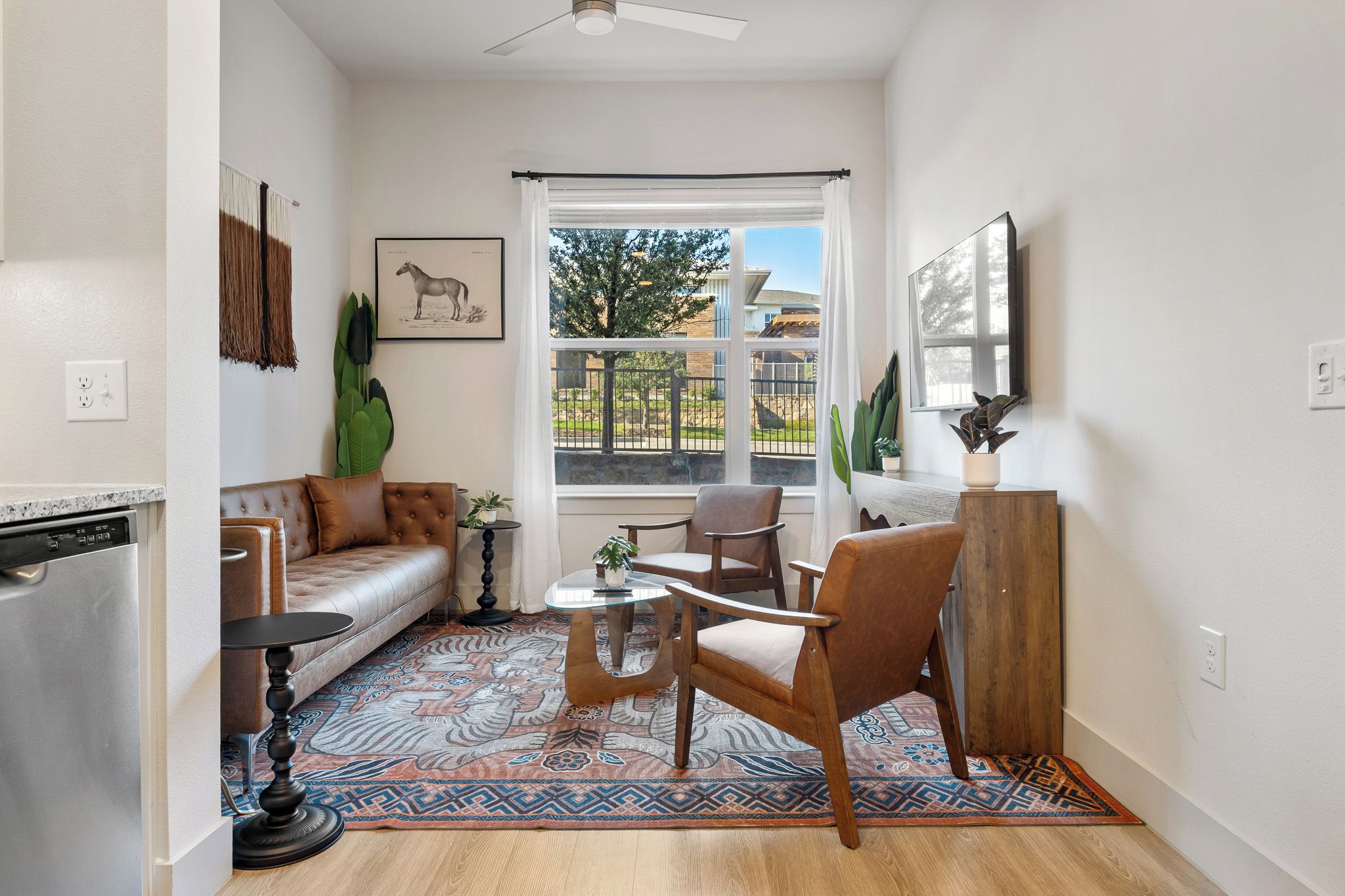 A modern living room with a sofa, chairs, a coffee table, and a patterned rug.