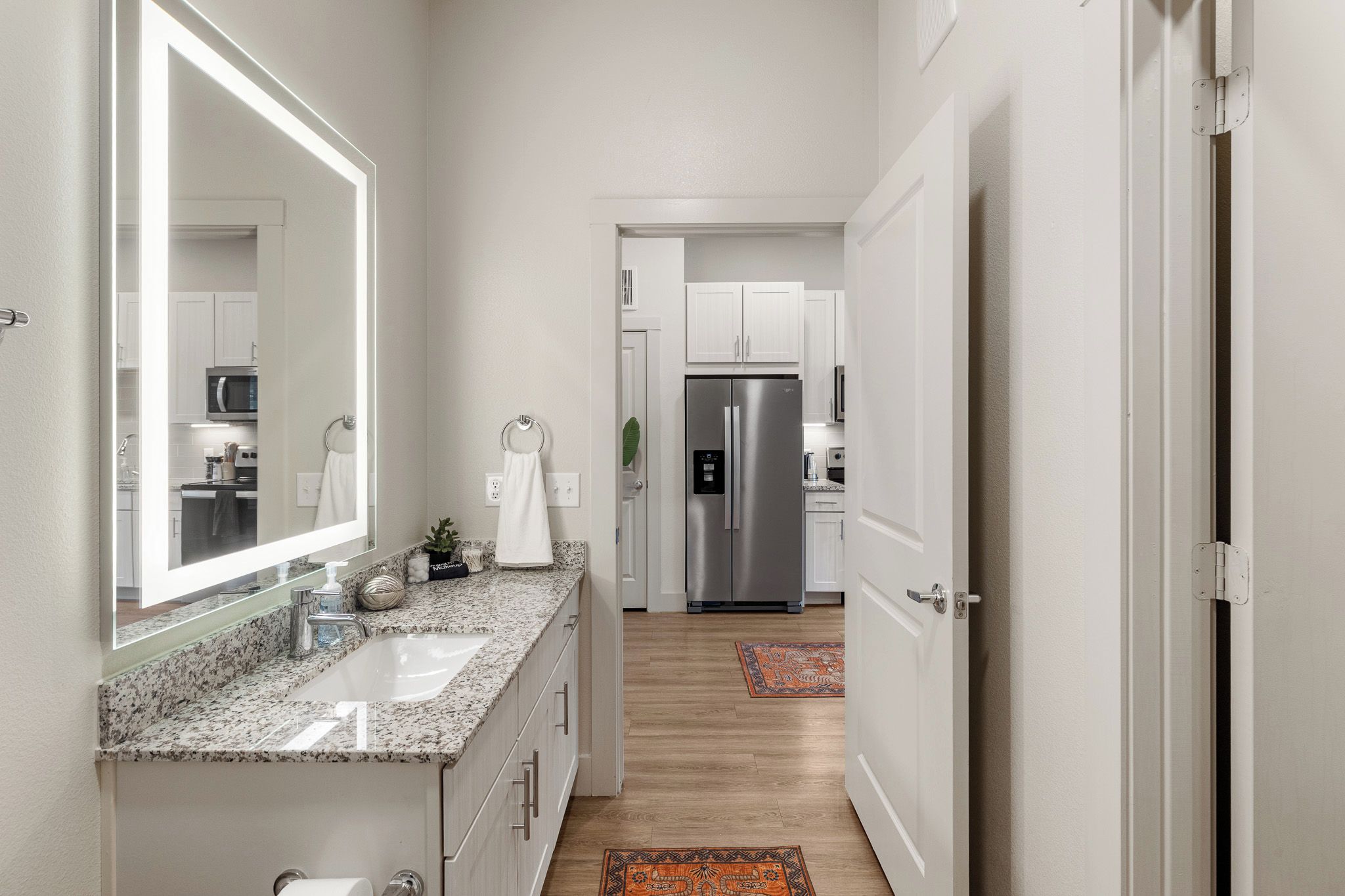 A modern kitchen with stainless steel appliances, a granite countertop, and a large mirror.