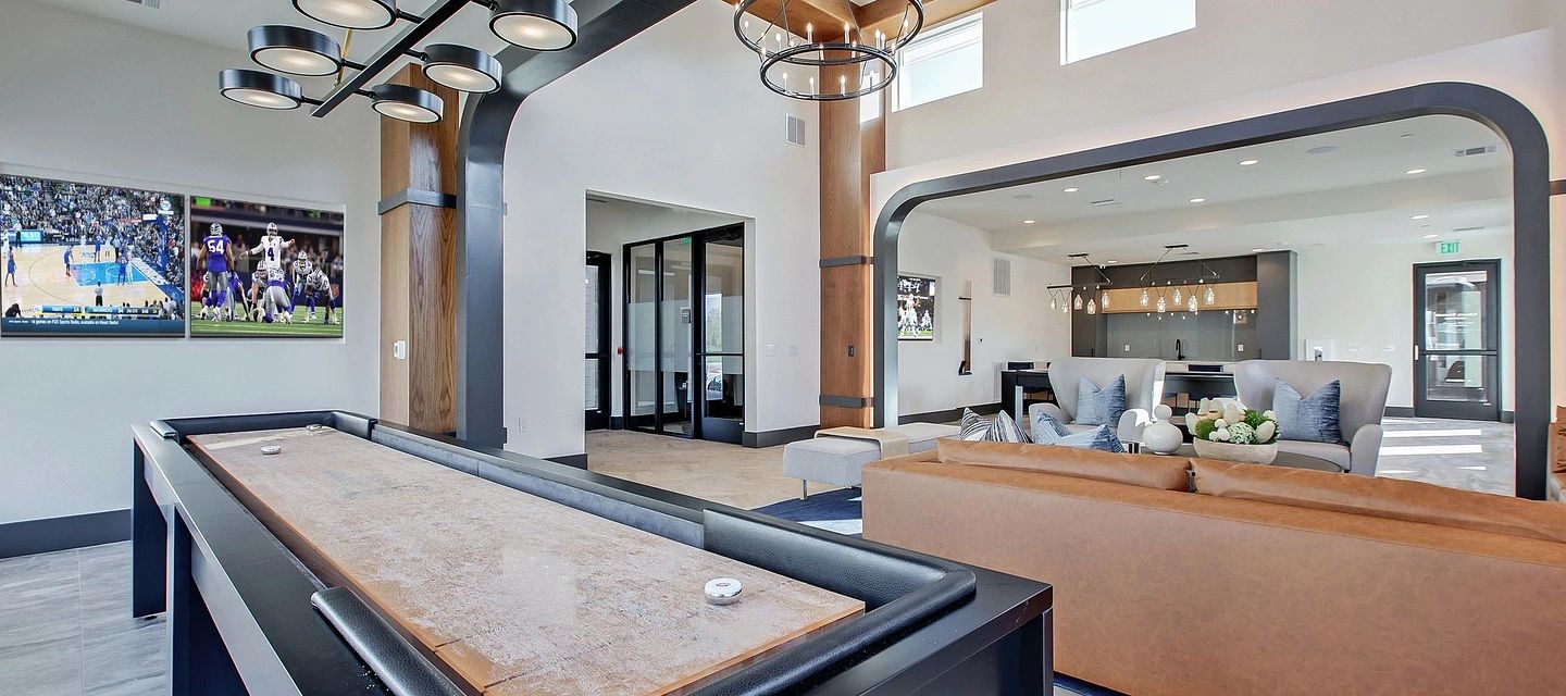 A billiards table in a modern room with a sofa and a mirror reflecting the room.