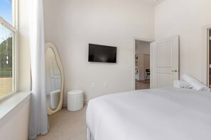 Habitación de hotel con una cama, televisor en la pared, una puerta y una ventana.