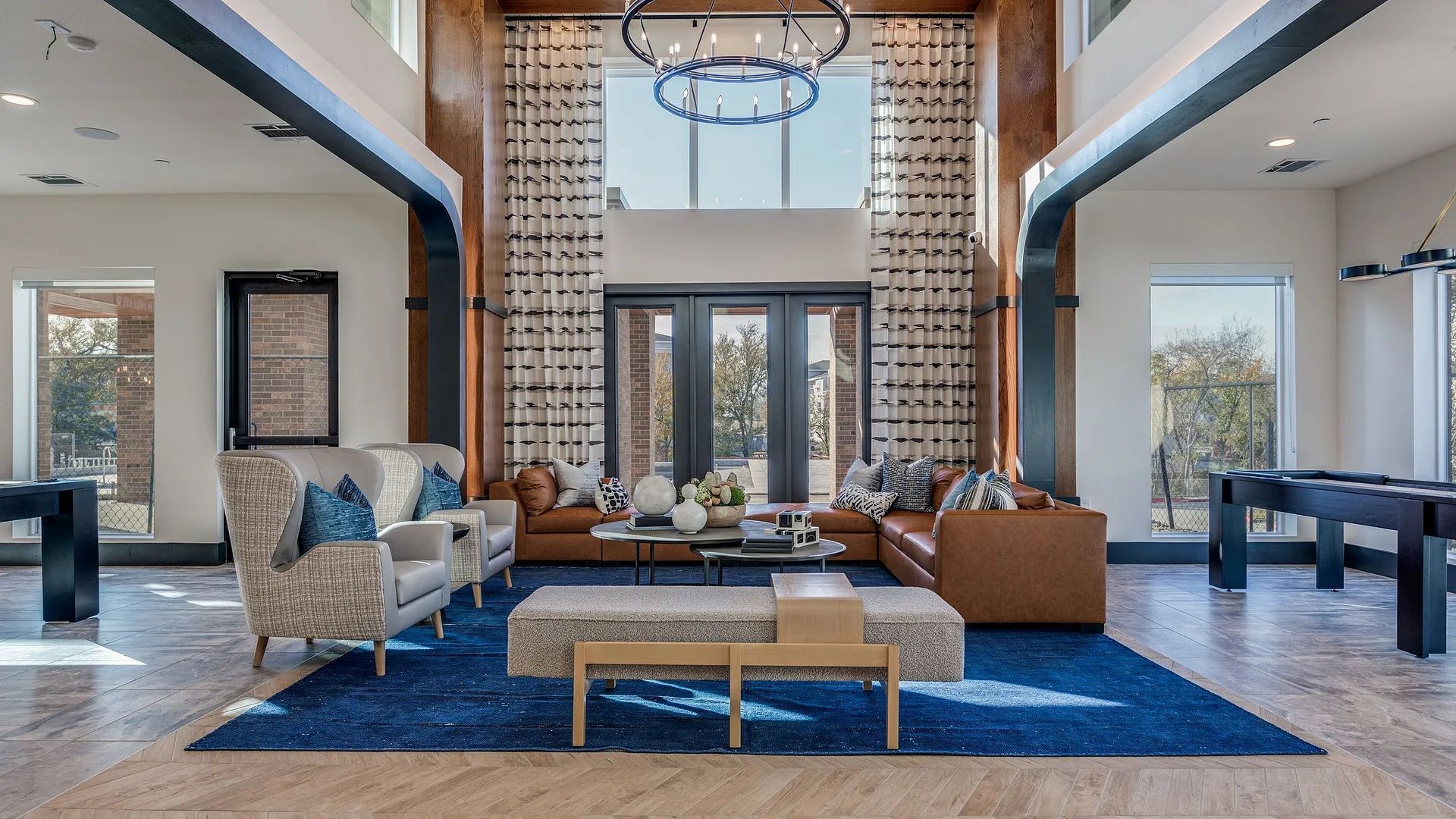 A spacious living room with a large window, a billiards table, and a fireplace.