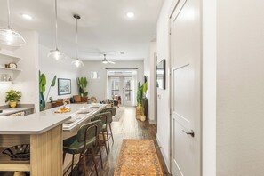 Una cocina moderna con una isla central, iluminación colgante y vistas al área de comedor.