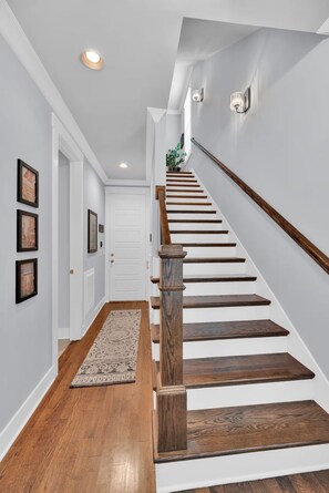 A staircase with wooden steps and a handrail, leading to a landing with a white door and framed pictures on the wall. - 3bed/3bth Just Minutes from Downtown (Nashville)