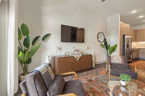 Een moderne woonkamer met een bank, salontafel en een televisie aan de muur.