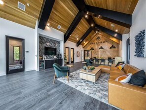 Ein geräumiger Wohnbereich mit modernem Design, der ein Holzboden, ein Kamin und eine Sitzecke mit Sofa und Sesseln bietet.