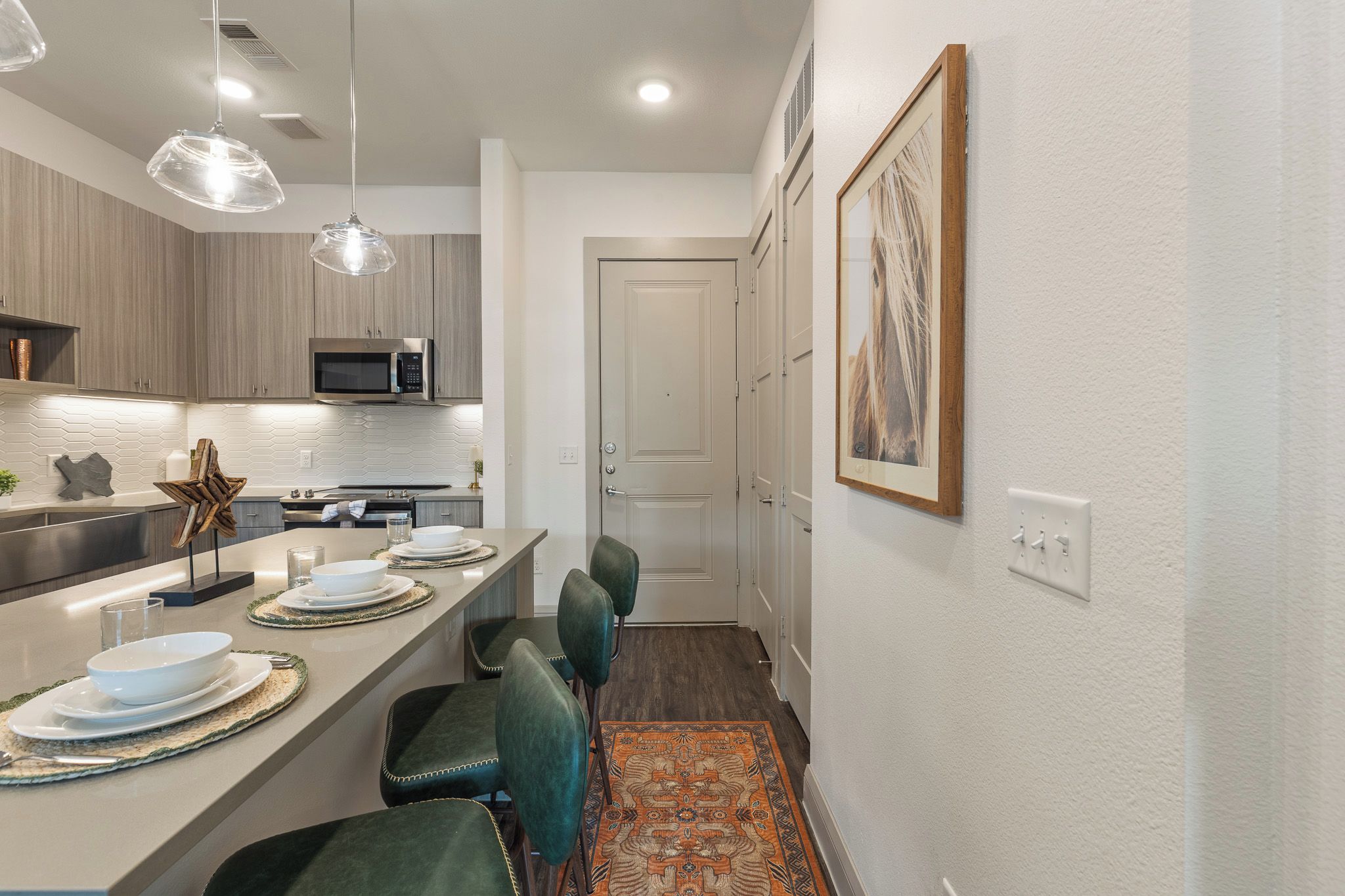 Una cocina moderna con una isla central, iluminación colgante y una zona de comedor con sillas.