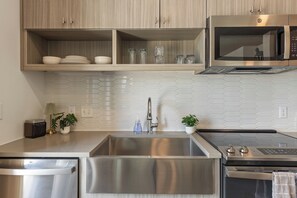 Une cuisine moderne dotée d’appareils électroménagers en acier inoxydable, d’un évier à deux bacs et d’un four à micro-ondes placé au-dessus de la cuisinière.