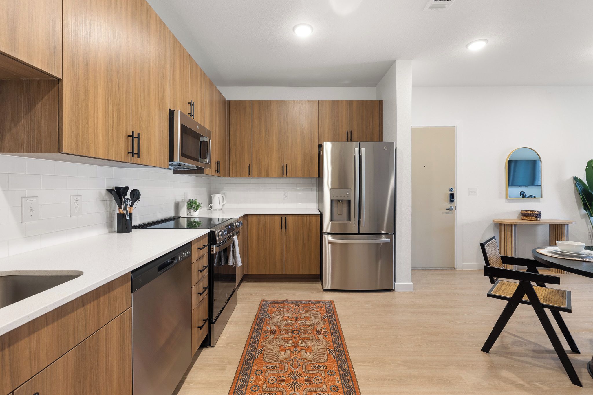Una cocina moderna con armarios de madera, electrodomésticos de acero inoxidable y una zona de comedor con mesa y sillas.