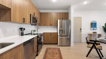Una cocina moderna con armarios de madera, electrodomésticos de acero inoxidable y una zona de comedor con mesa y sillas.