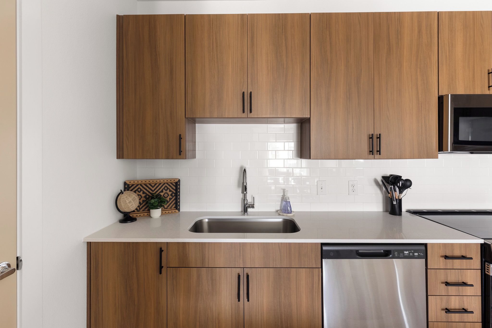 Una cocina con armarios de madera, un lavamanos de acero inoxidable y un lavavajillas.