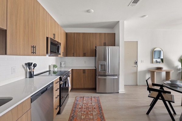 Een moderne keuken met houten kastjes, roestvrijstalen apparatuur en een eethoek met een tafel en stoelen.