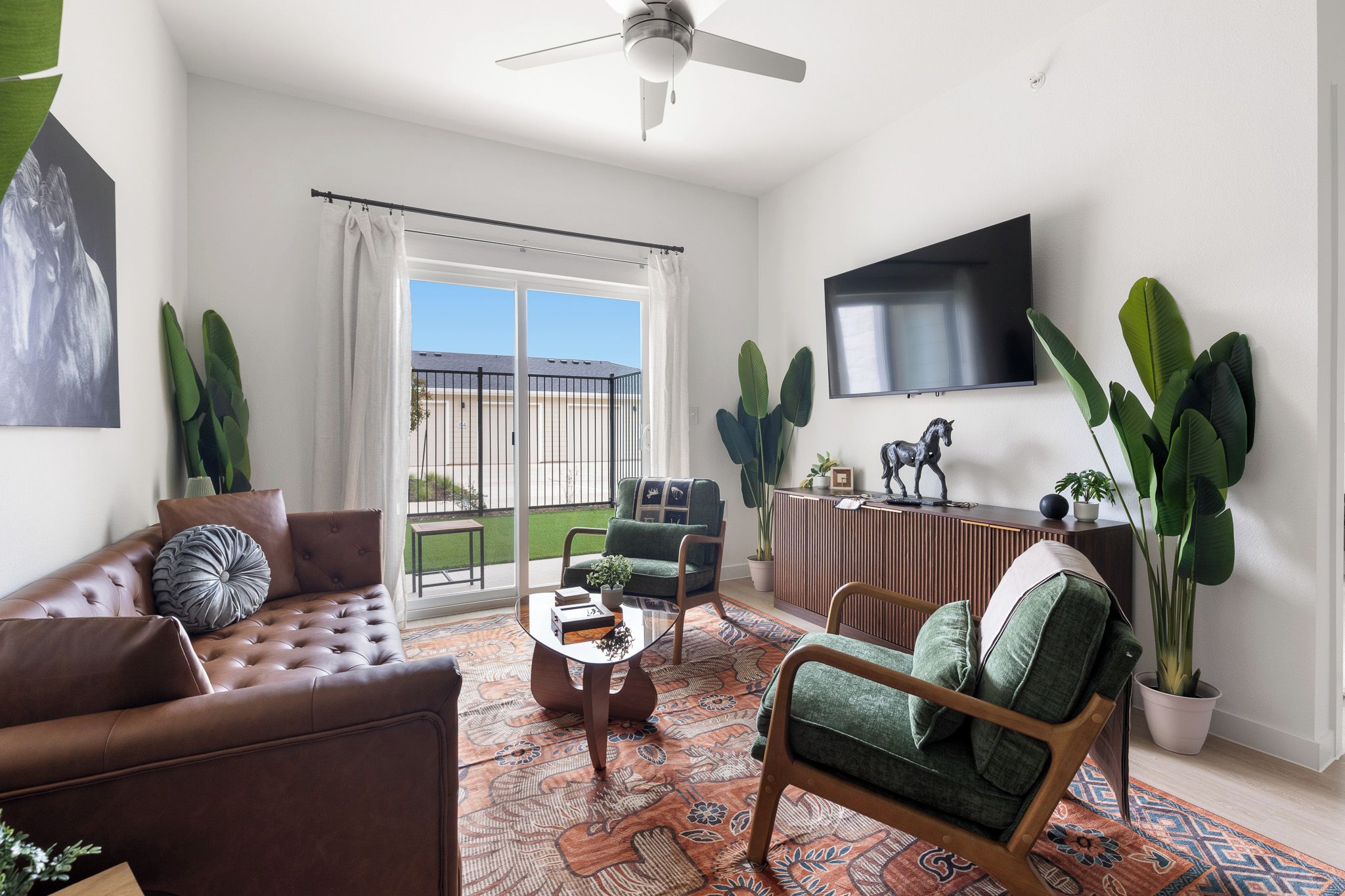 A living room with a sofa, armchair, coffee table, and a TV mounted on the wall.