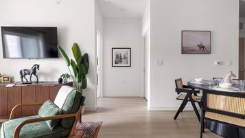 A modern living room with a television, a horse sculpture, and a dining area with a table and chairs.